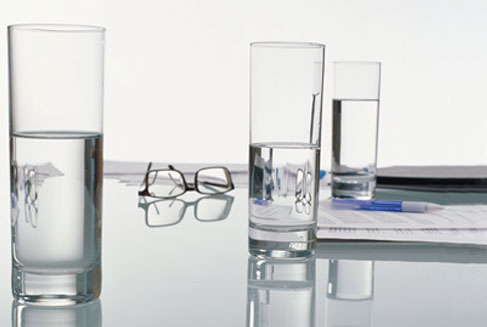 Gläser, Akten und Brille auf Glastisch